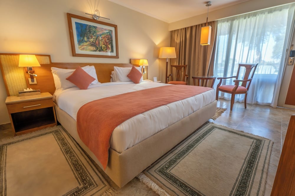 Jolie Ville Hotel & Spa Kings Island Luxor guest bedroom with a king bed and a window-side seating area.