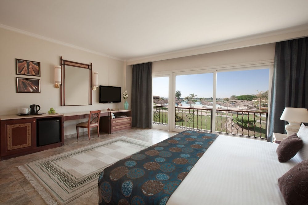 Jolie Ville Hotel & Spa Kings Island Luxor guest room with a bed and sliding glass doors.