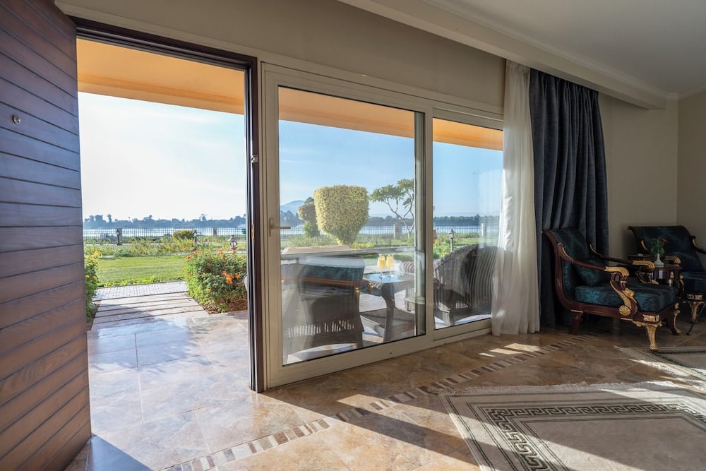 Jolie Ville Hotel & Spa Kings Island Luxor guest room with sliding glass doors and garden views.
