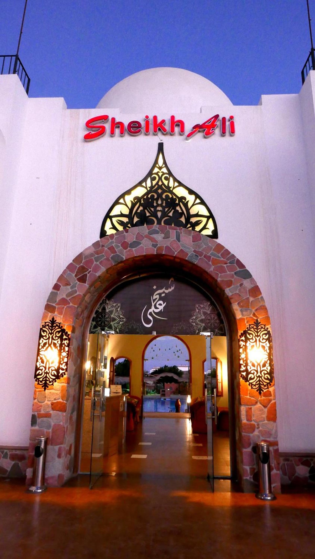 Sheikh Ali Dahab Resort entrance with a stone arch and ornate metalwork.