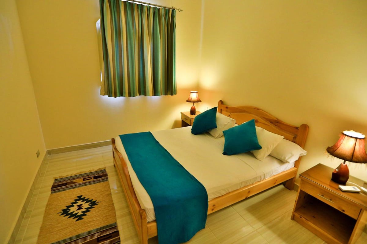 Sheikh Ali Dahab Resort bedroom with a wooden bed and teal bedding.