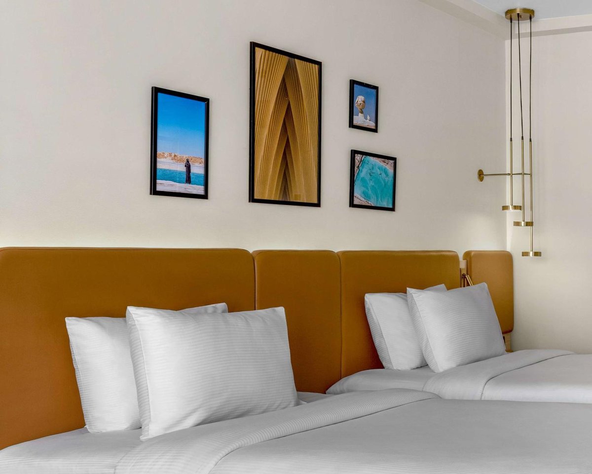 Hilton Alexandria Green Plaza guest bedroom with two beds and a mustard headboard.
