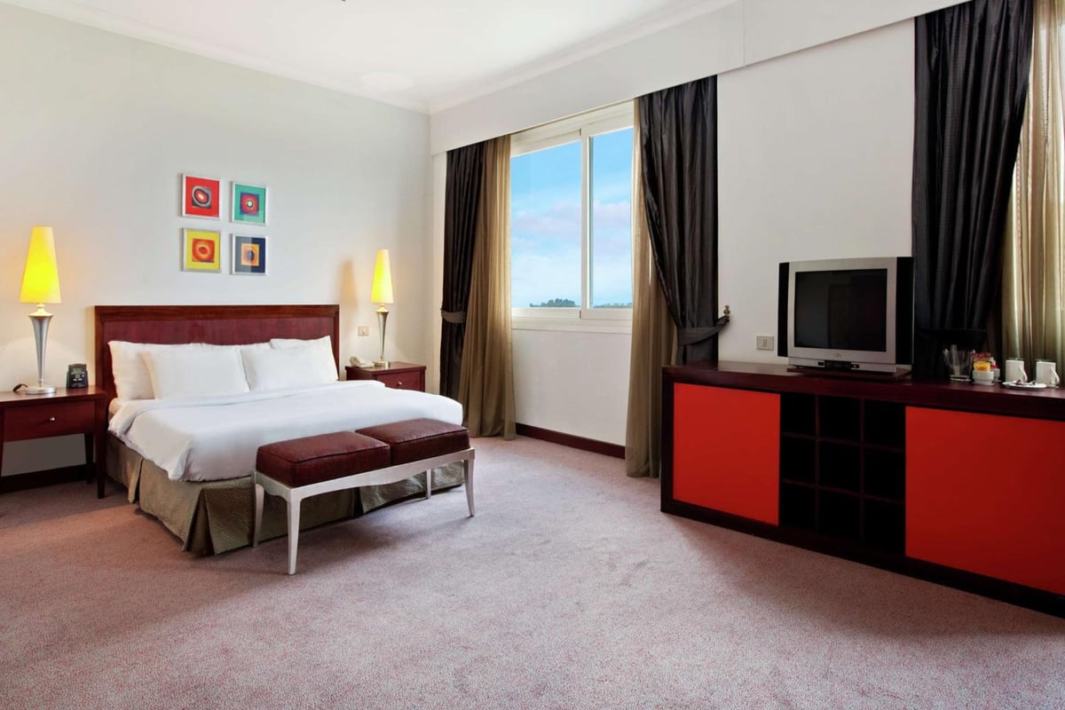 Hilton Alexandria Green Plaza bedroom with a white bed and curtained window.