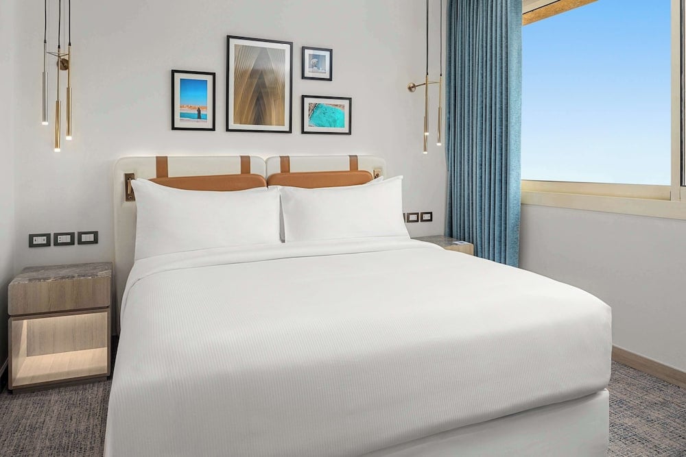 Hilton Alexandria Green Plaza bedroom with a white bed and blue curtains.