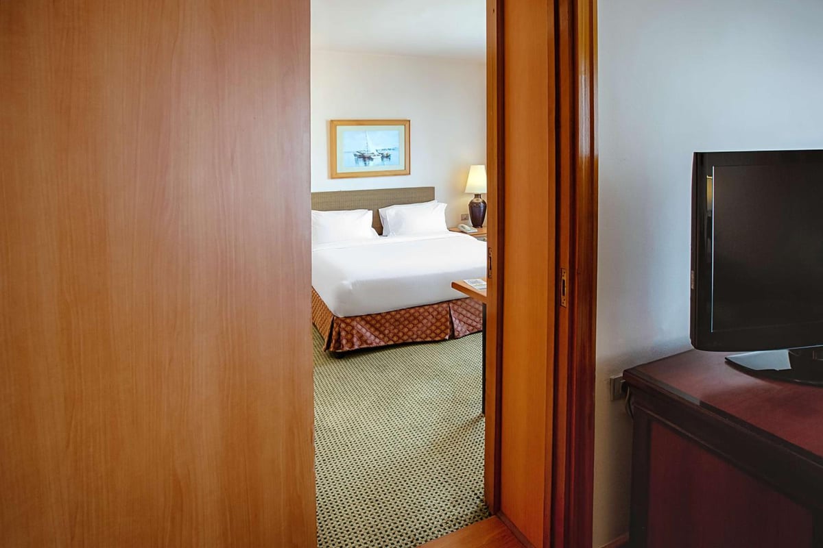 Hilton Alexandria Green Plaza bedroom with a white bed and patterned carpet.
