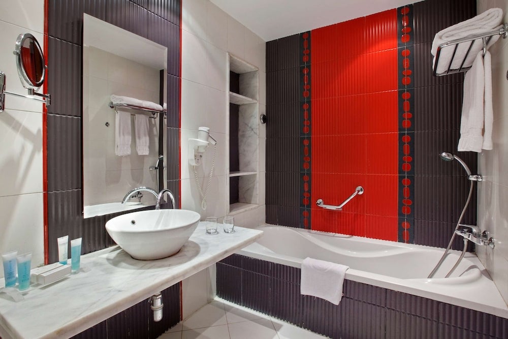 Hilton Alexandria Green Plaza bathroom with a bathtub and red accent wall.
