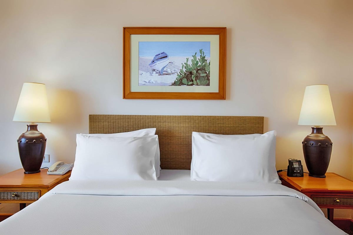Hilton Alexandria Green Plaza bedroom with a neatly made bed and woven headboard.