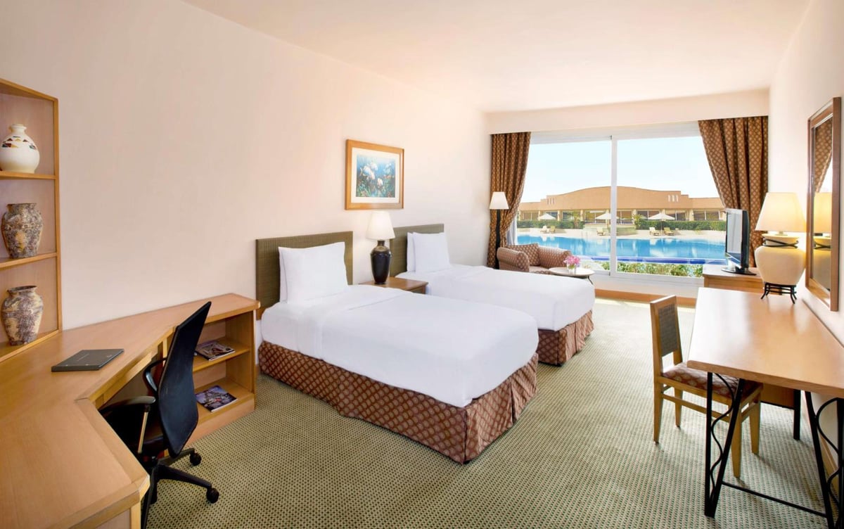 Hilton Alexandria Green Plaza twin guest room with twin beds and a pool view.