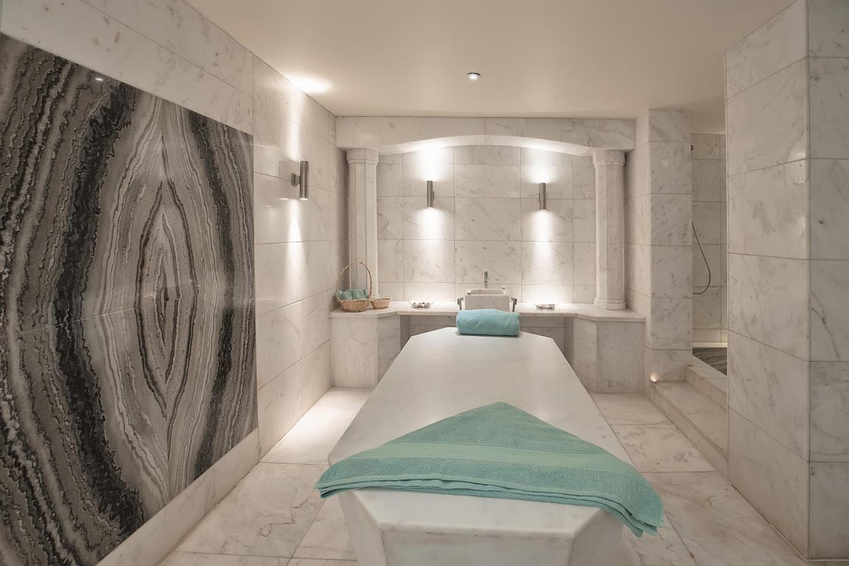 Hilton Alexandria Green Plaza spa treatment room with a massage table and marble walls.