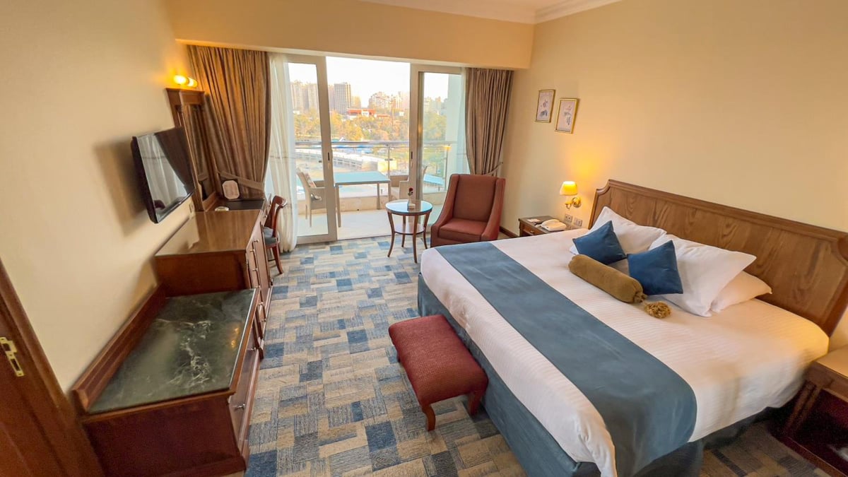 Palestine Montaza Alexandria hotel bedroom with a large bed and glass balcony doors.