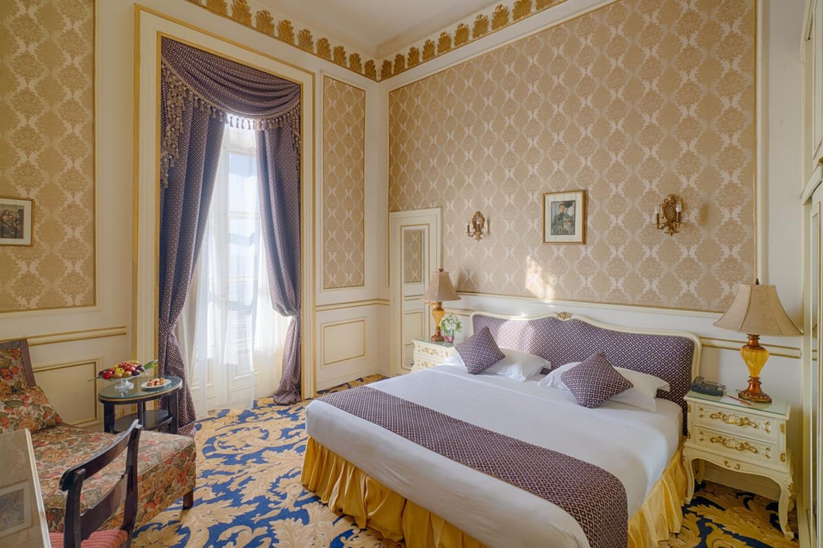 Le Metropole Hotel Alexandria bedroom with a large bed and patterned walls.