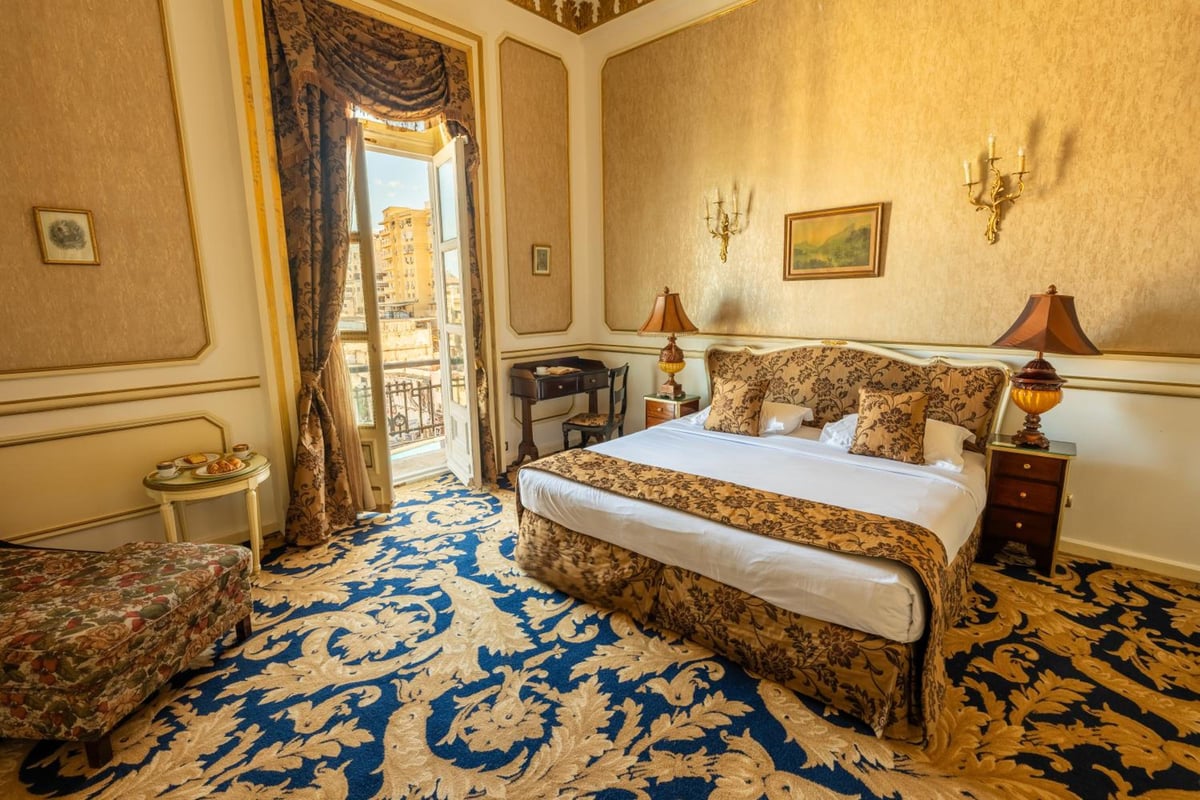 Le Metropole Hotel Alexandria bedroom with an ornate bed and balcony doors.