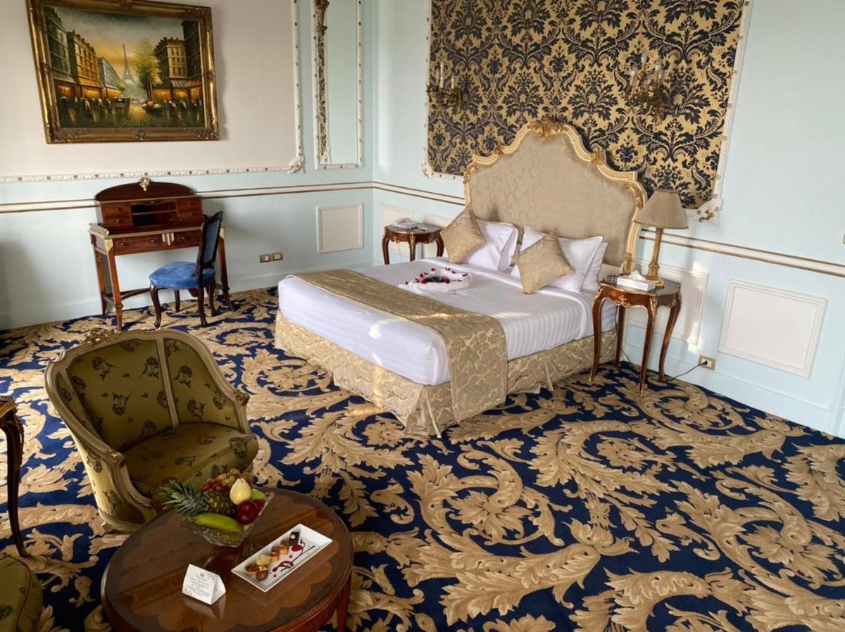 Le Metropole Hotel Alexandria bedroom with an ornate bed and patterned carpet.