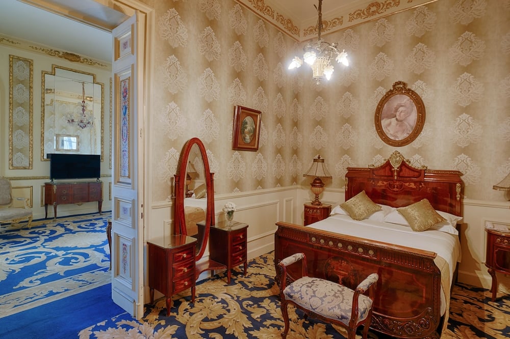 Le Metropole Hotel Alexandria bedroom with a carved wooden bed and patterned carpet.