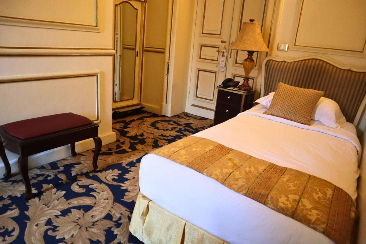 Le Metropole Hotel Alexandria guest room with a striped headboard and patterned carpet.