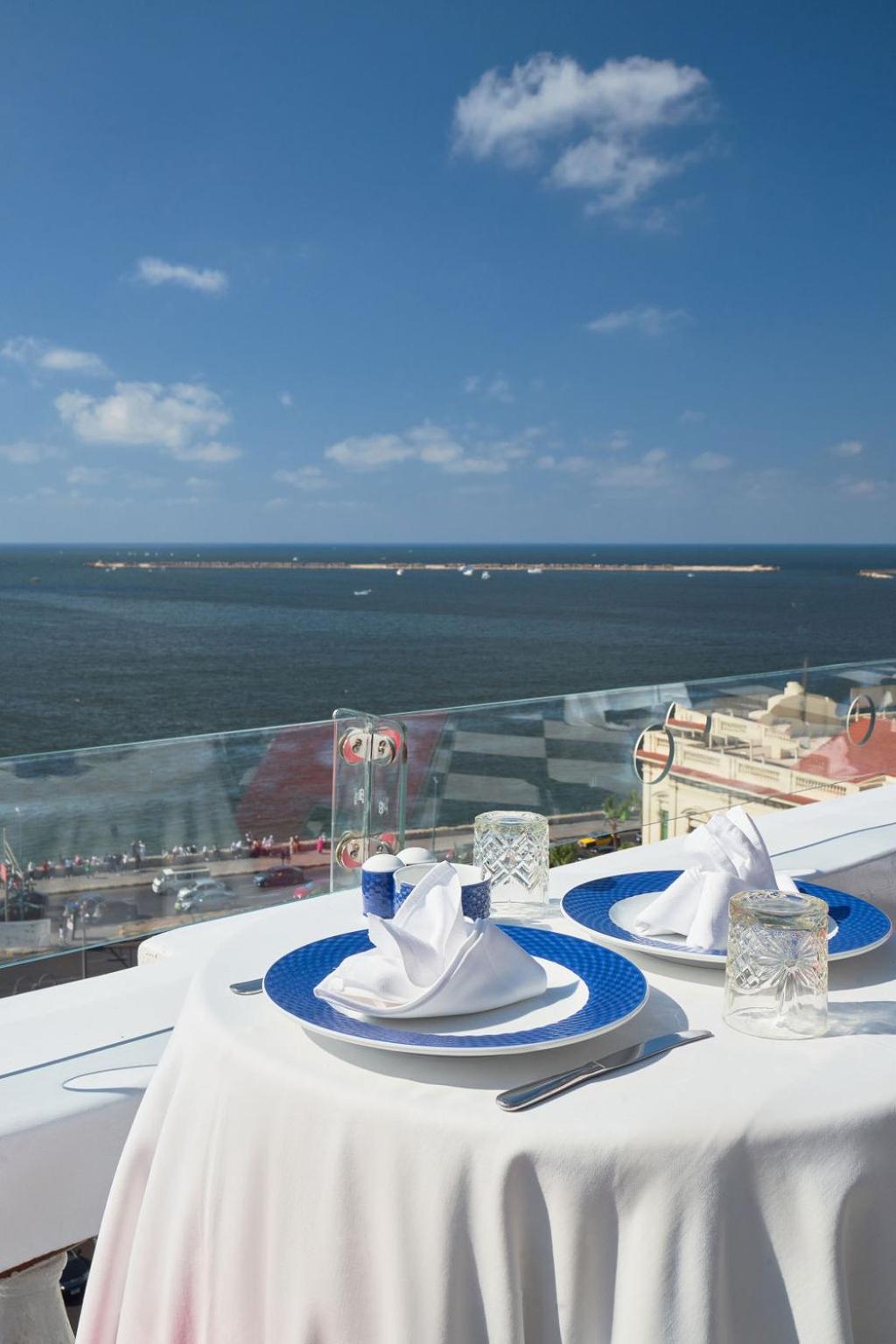 Le Metropole Hotel Alexandria terrace with a set dining table and sea view.