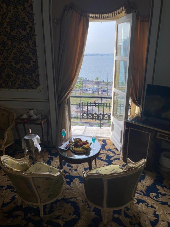 Le Metropole Hotel Alexandria sitting area with patterned chairs and open balcony doors.