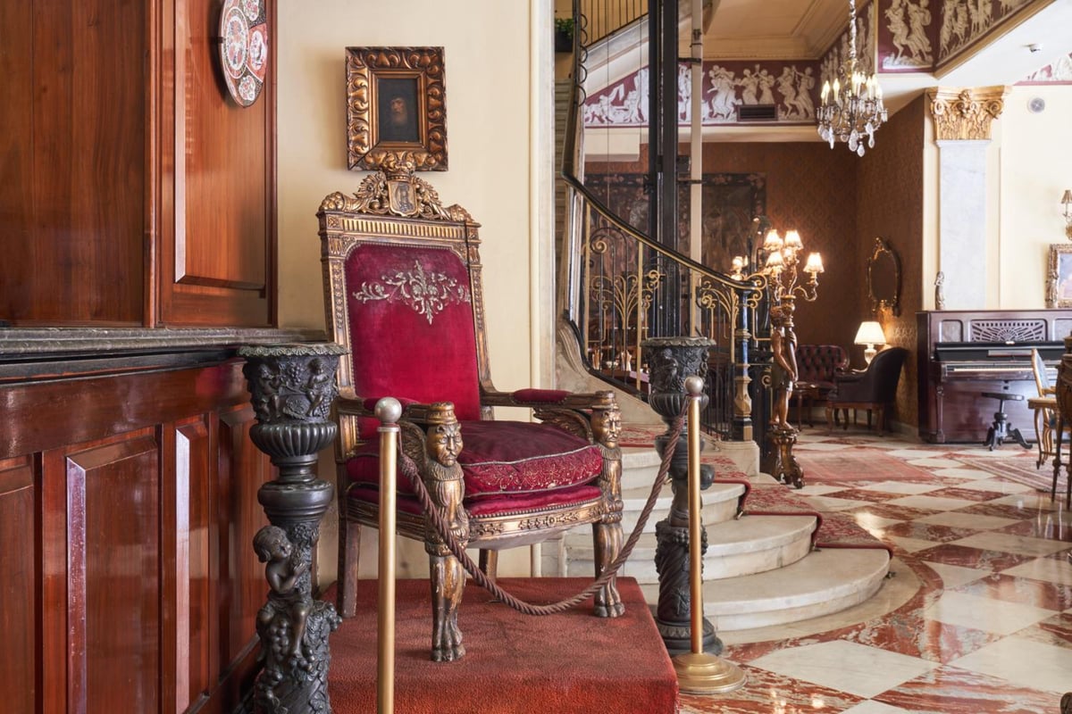 Le Metropole Hotel Alexandria lobby with a curved staircase and chandeliers.