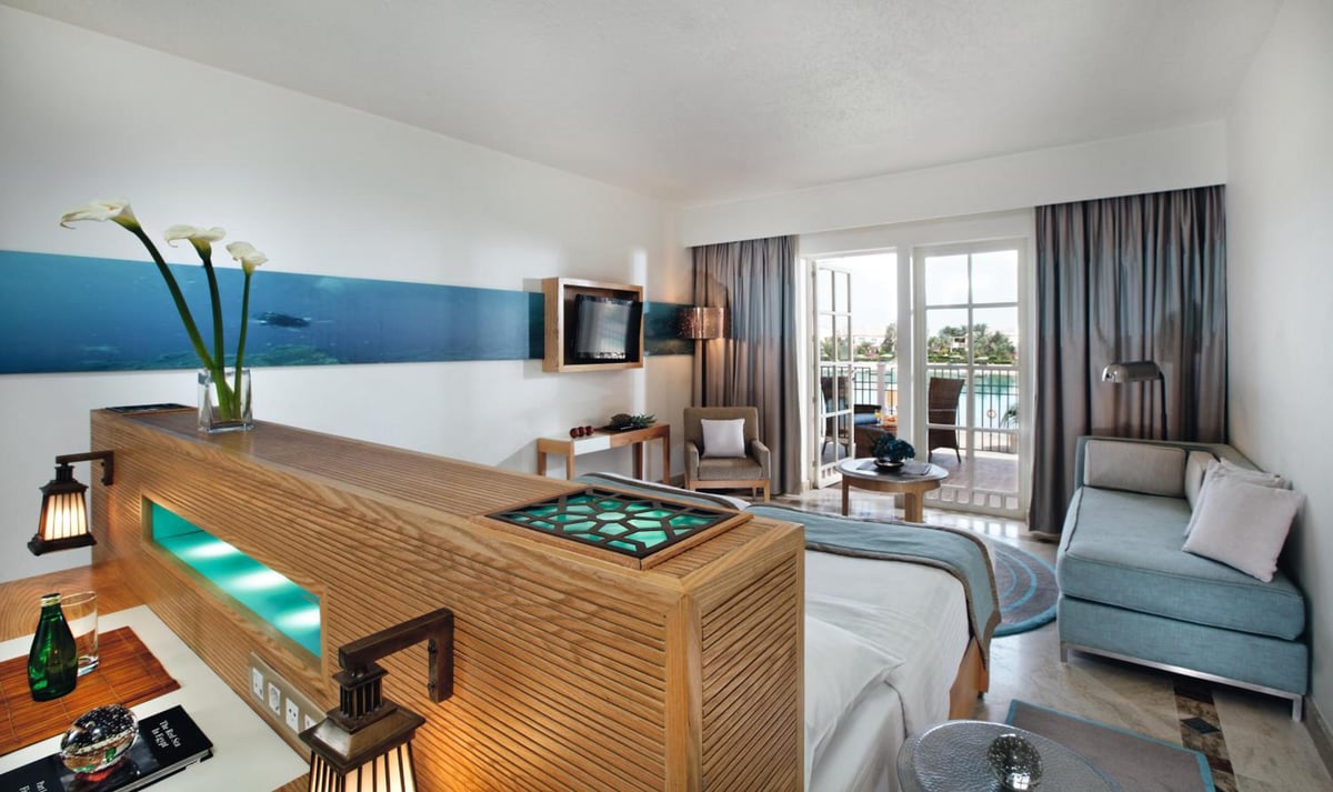 Movenpick Resort & Spa El Gouna guest room with a wood-slat divider and balcony doors.