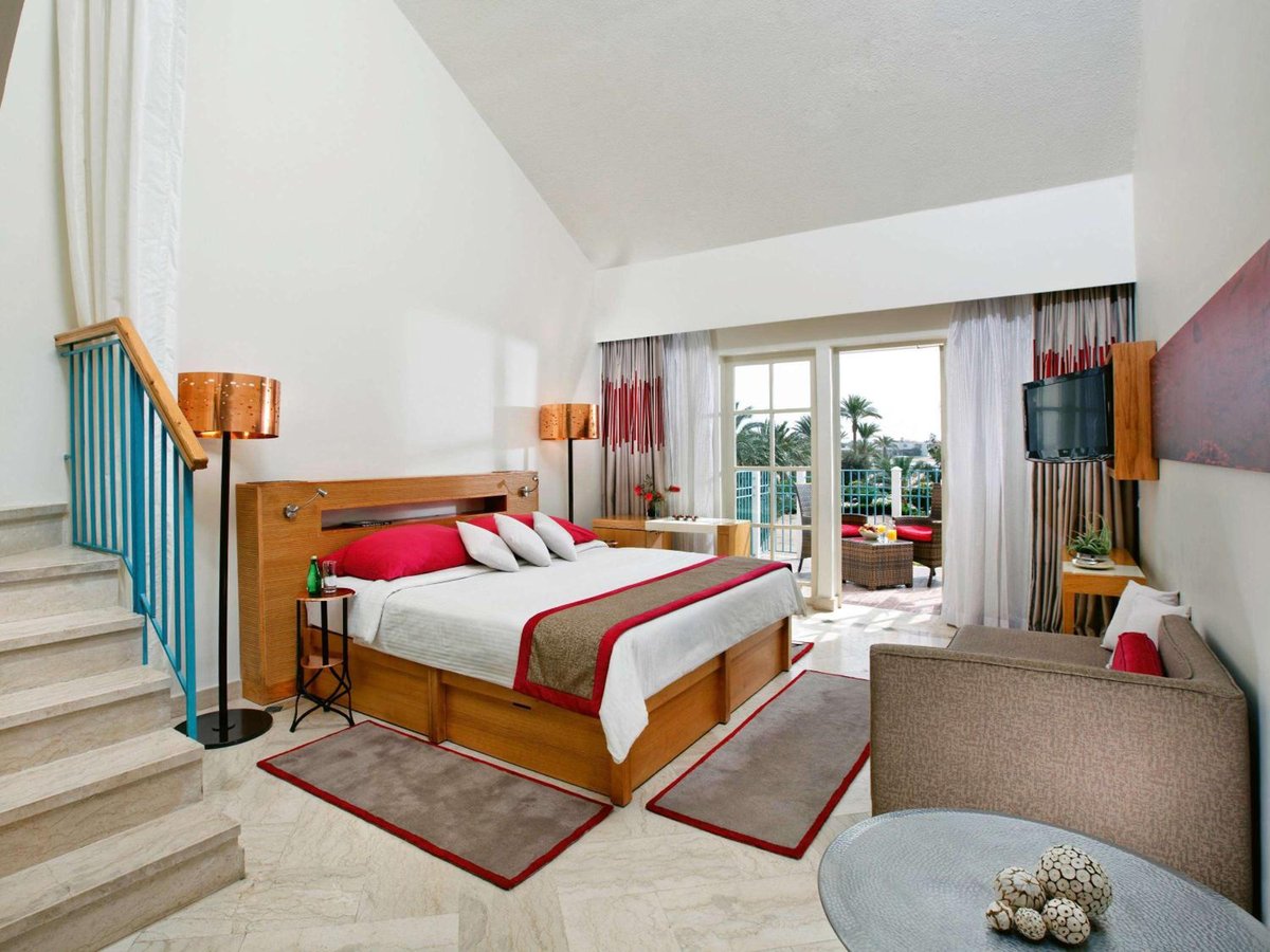 Movenpick Resort & Spa El Gouna duplex bedroom with a wooden bed and staircase.
