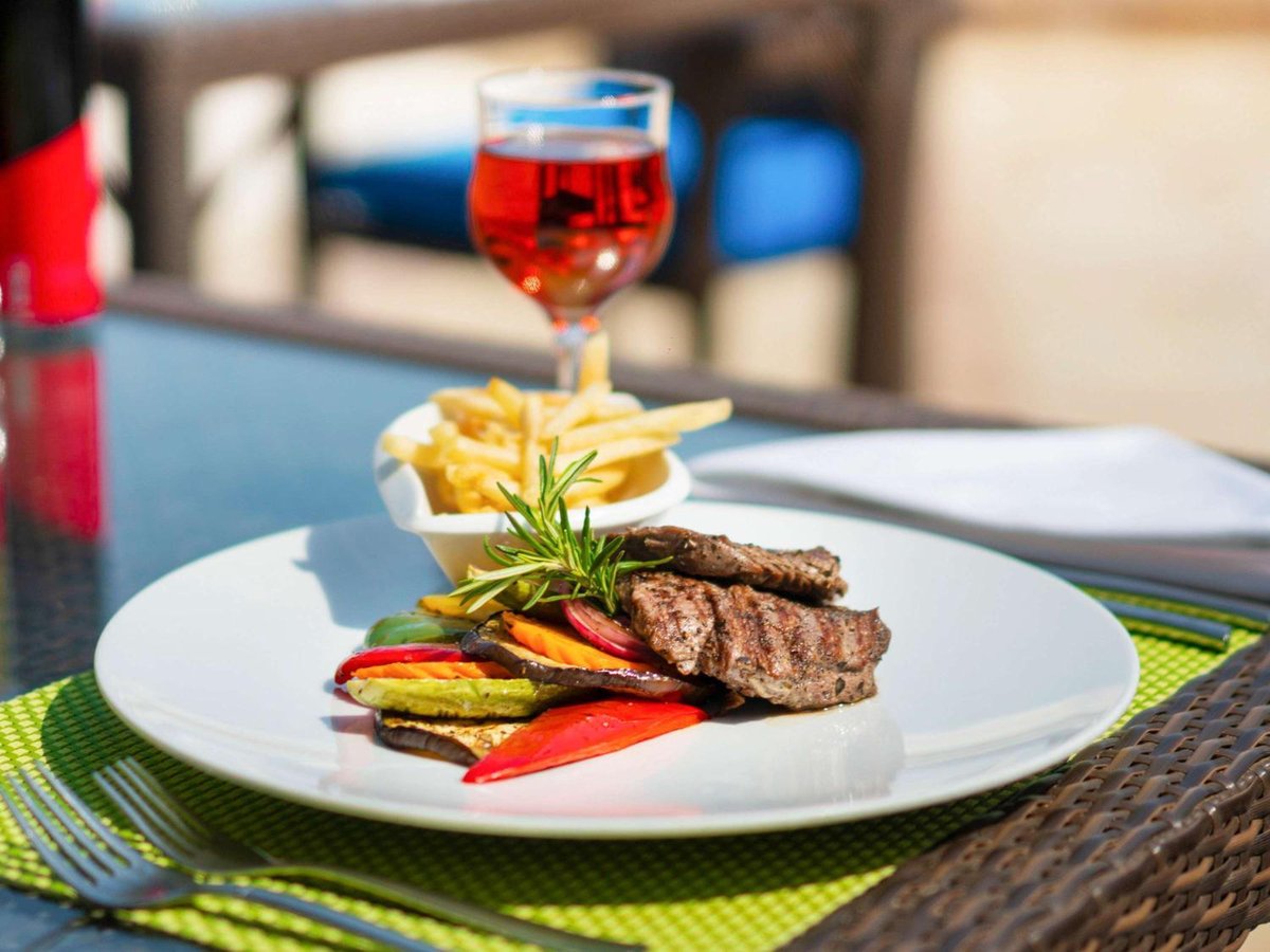 Movenpick Resort & Spa El Gouna dining table with grilled meat and red wine.