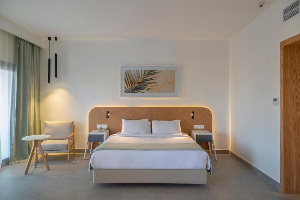 Amphoras Beach Ultra All Inclusive bedroom with a bed and a backlit wooden headboard.