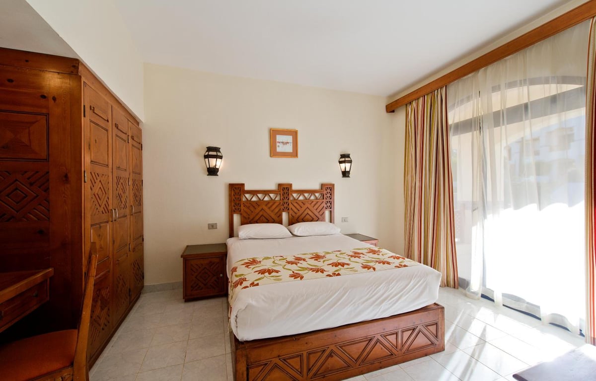 Amphoras Beach Ultra All Inclusive bedroom with a carved wooden bed and large glass doors.