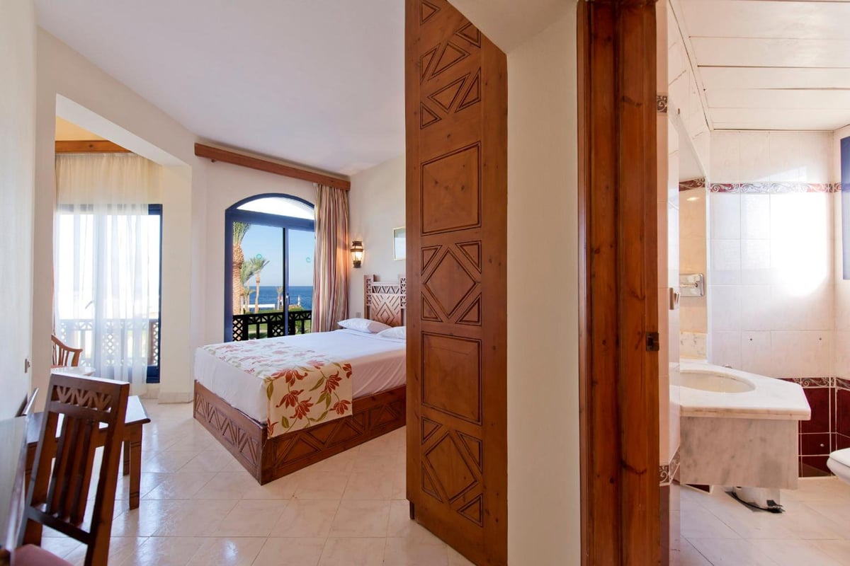 Amphoras Beach Ultra All Inclusive guest room with a carved wooden partition and an arched glass doorway.