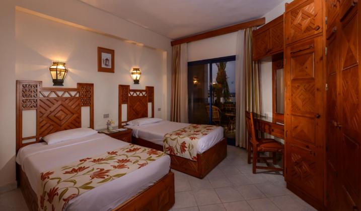 Amphoras Beach Ultra All Inclusive twin bedroom with two beds and carved wooden furniture.