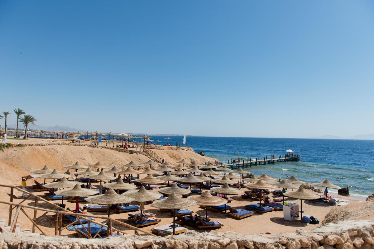 Amphoras Beach Ultra All Inclusive beach with thatched parasols and a rocky shoreline.