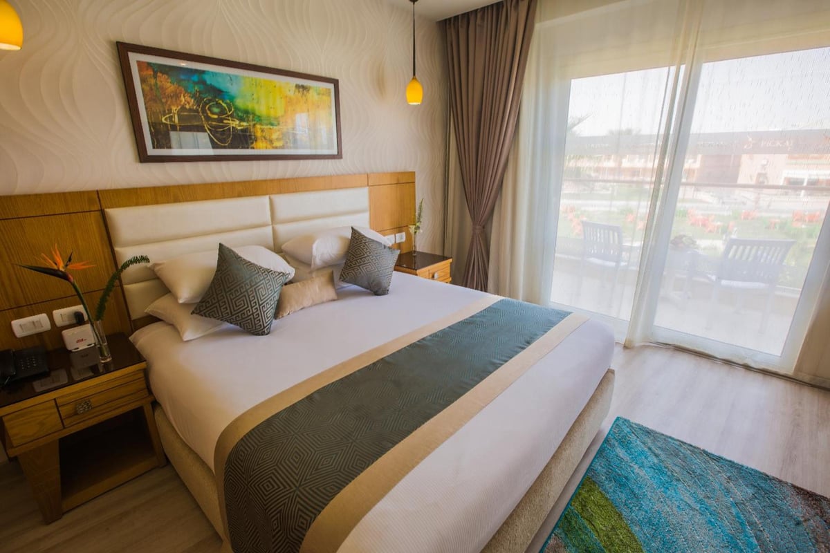 Pickalbatros Aqua Blu Sharm El Sheikh guest room with a large bed and sliding glass doors.