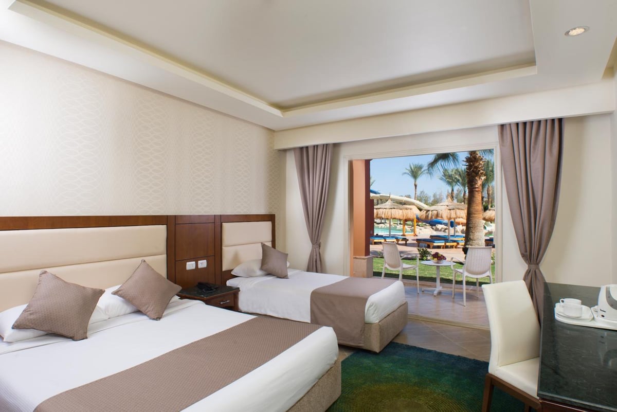 Pickalbatros Aqua Blu Sharm El Sheikh guest room with two beds and a balcony overlooking the pool.