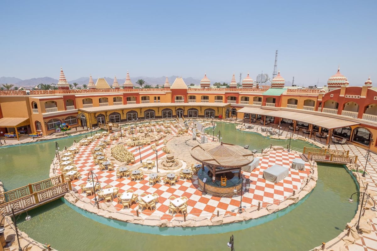 Pickalbatros Aqua Blu Sharm El Sheikh courtyard pool with a central island and checkerboard paving.