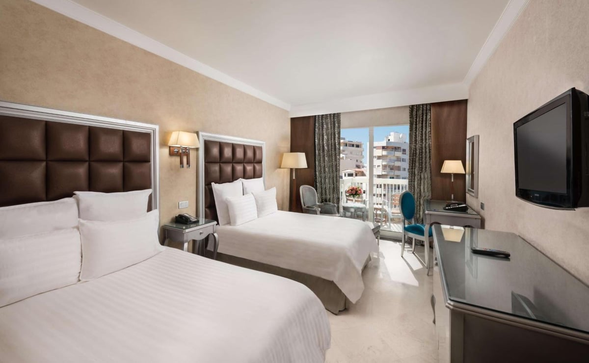 Hilton Alexandria Corniche guest room with twin beds and large windows.