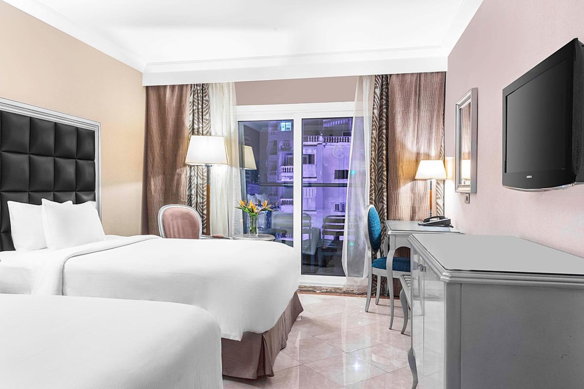 Hilton Alexandria Corniche guest room with two beds and sliding glass doors.
