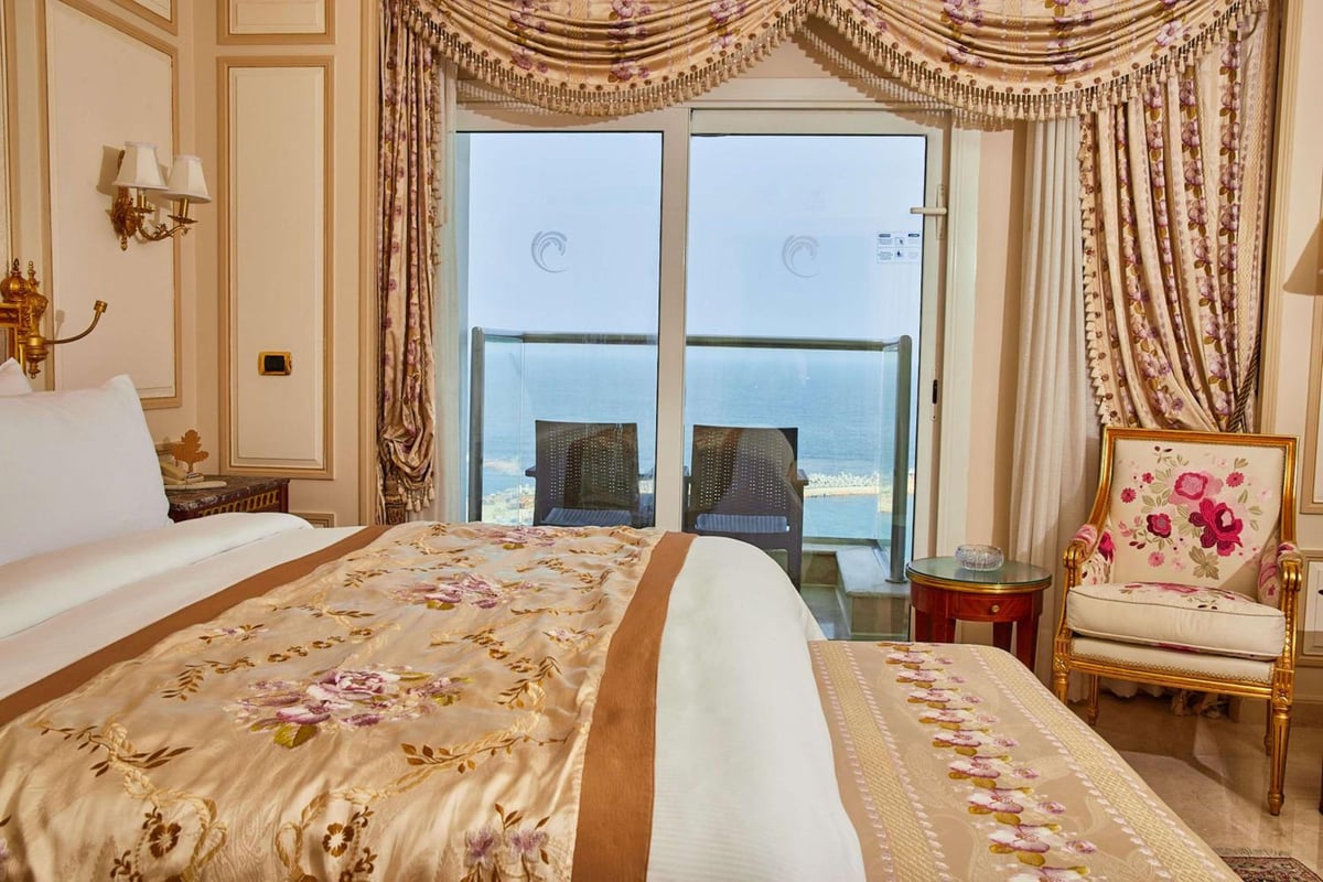Hilton Alexandria Corniche bedroom with a sea-view balcony and floral bedding.