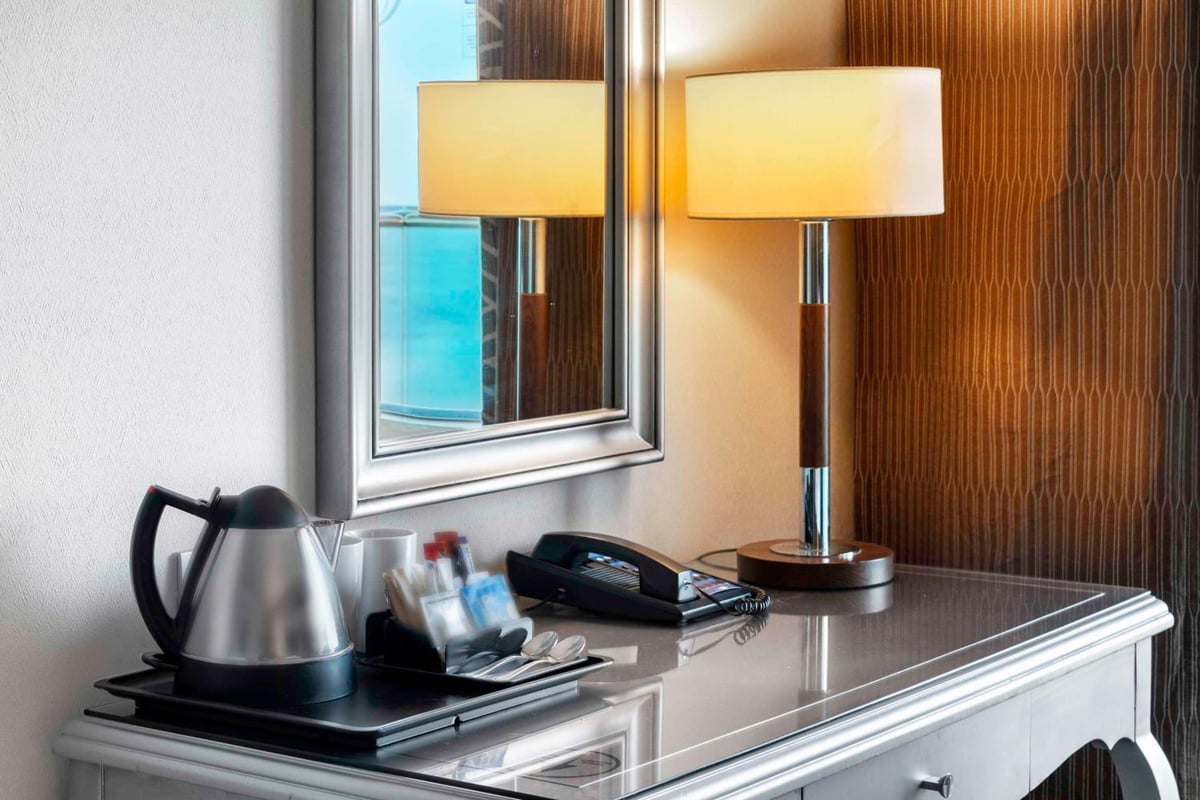 Hilton Alexandria Corniche guest room desk with a table lamp and wood-paneled wall.