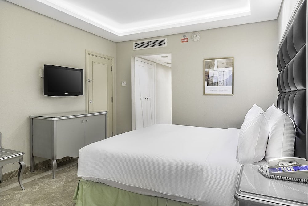 Hilton Alexandria Corniche guest room with a white bed and padded headboard.