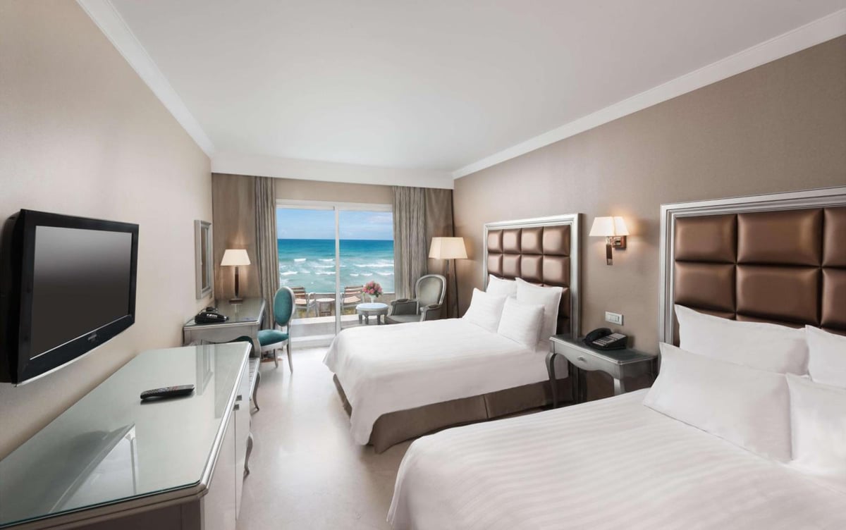Hilton Alexandria Corniche guest room with two beds and a sea view.