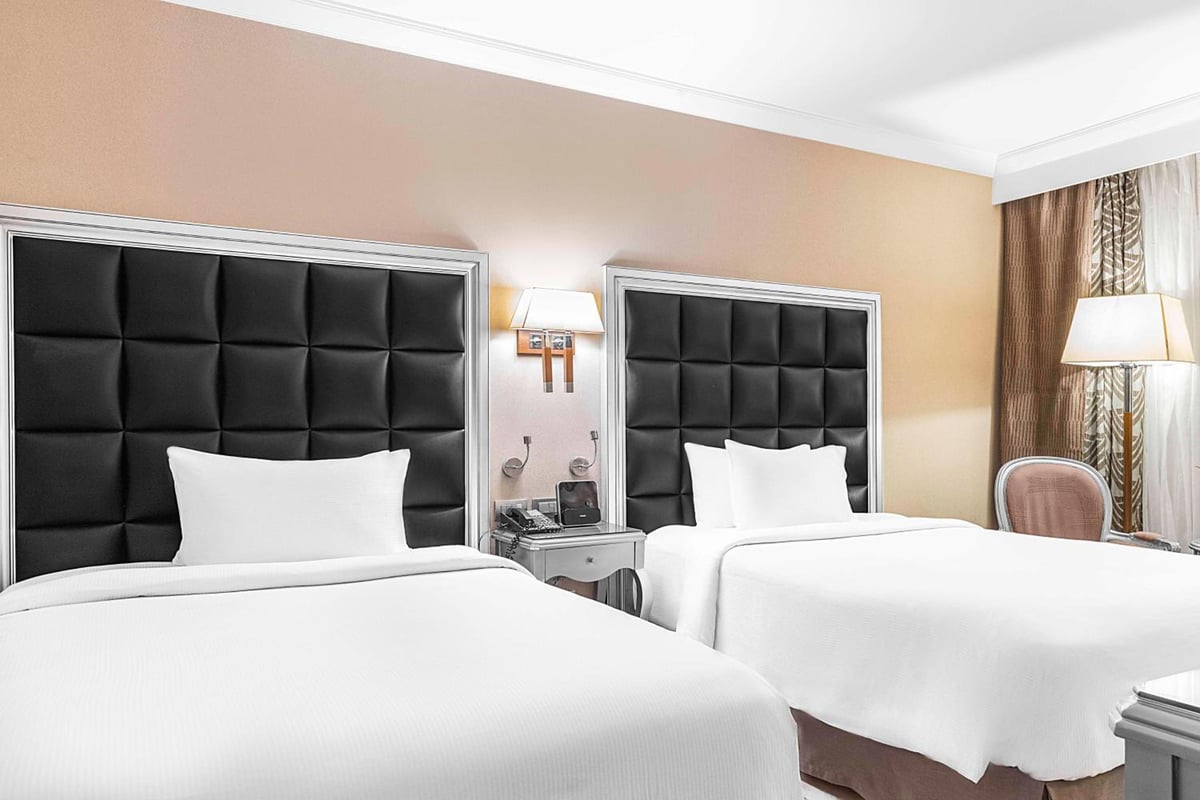 Hilton Alexandria Corniche guest room with twin beds and black padded headboards.