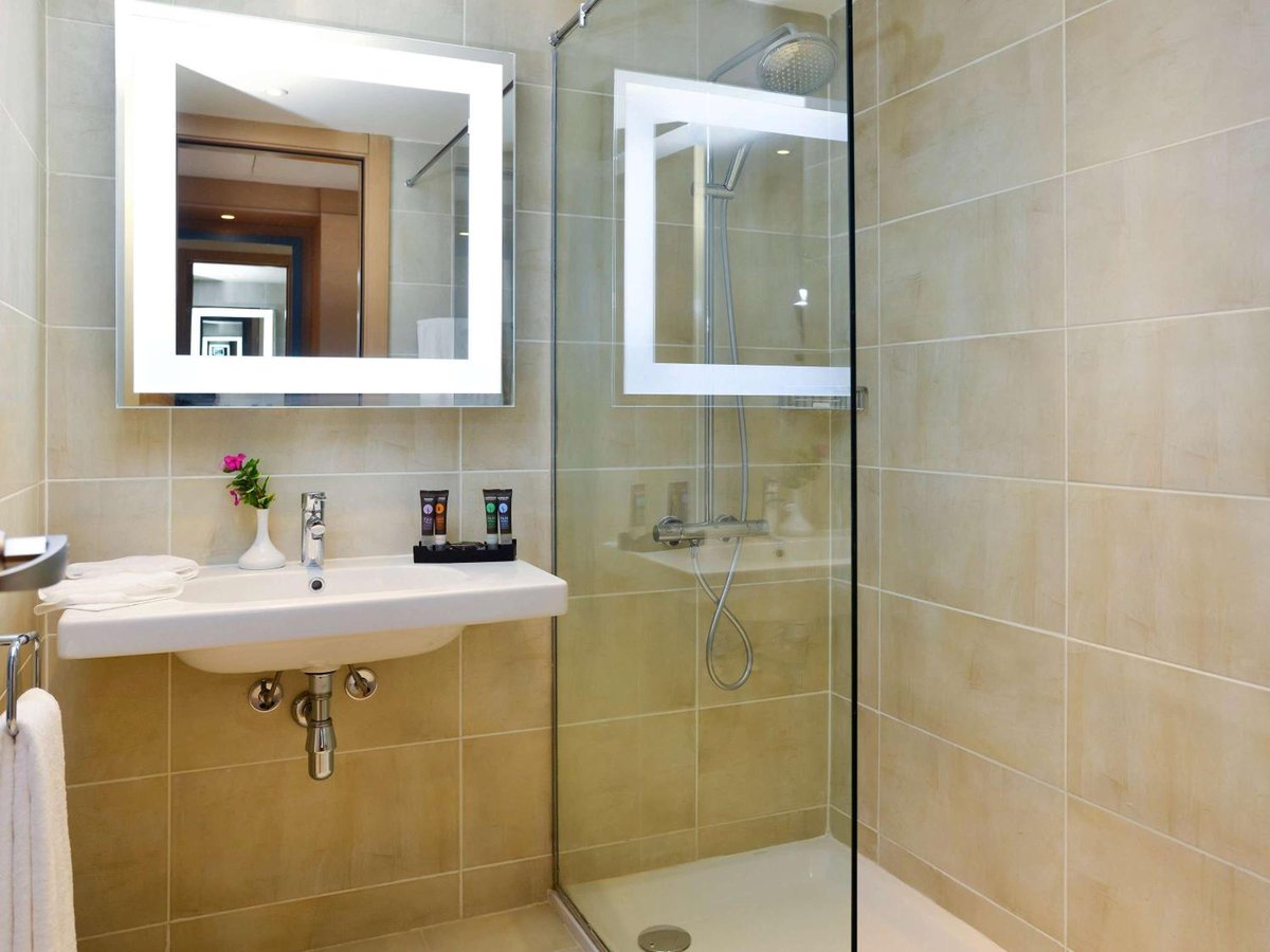 Novotel Marsa Alam Beach Resort bathroom with a wall-mounted sink and glass shower enclosure.