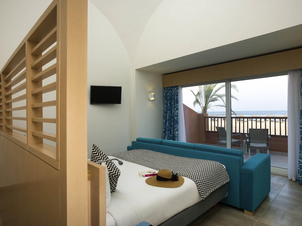 Novotel Marsa Alam Beach Resort guest room with a patterned bedspread and glass doors to a balcony.