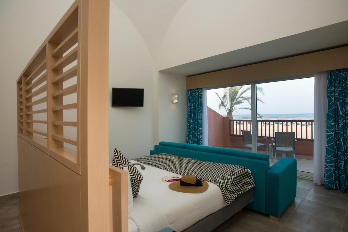 Novotel Marsa Alam Beach Resort guest room with a bed and teal sofa.