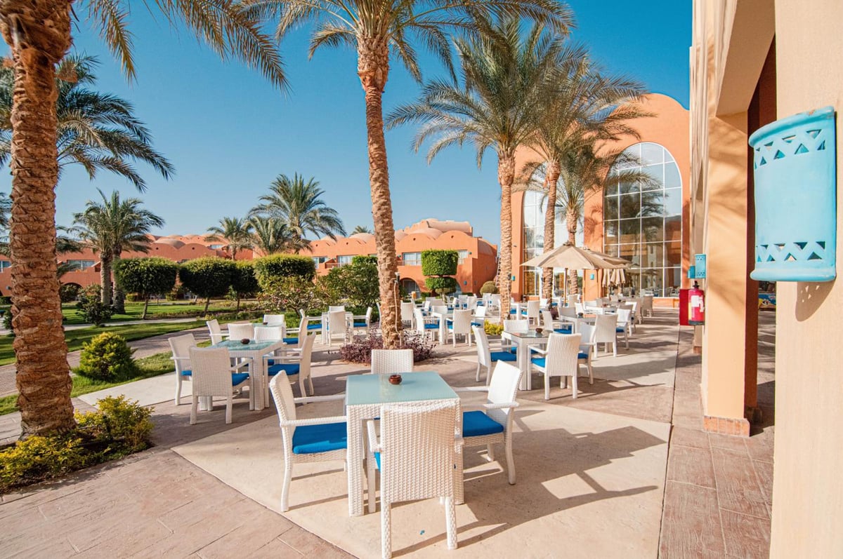 Novotel Marsa Alam Beach Resort outdoor dining terrace with white tables and palm trees.