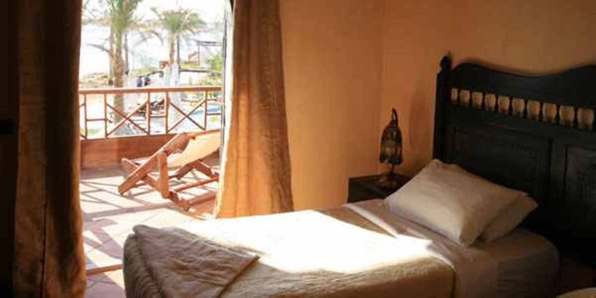Dahab Paradise bedroom with a dark headboard and a balcony.