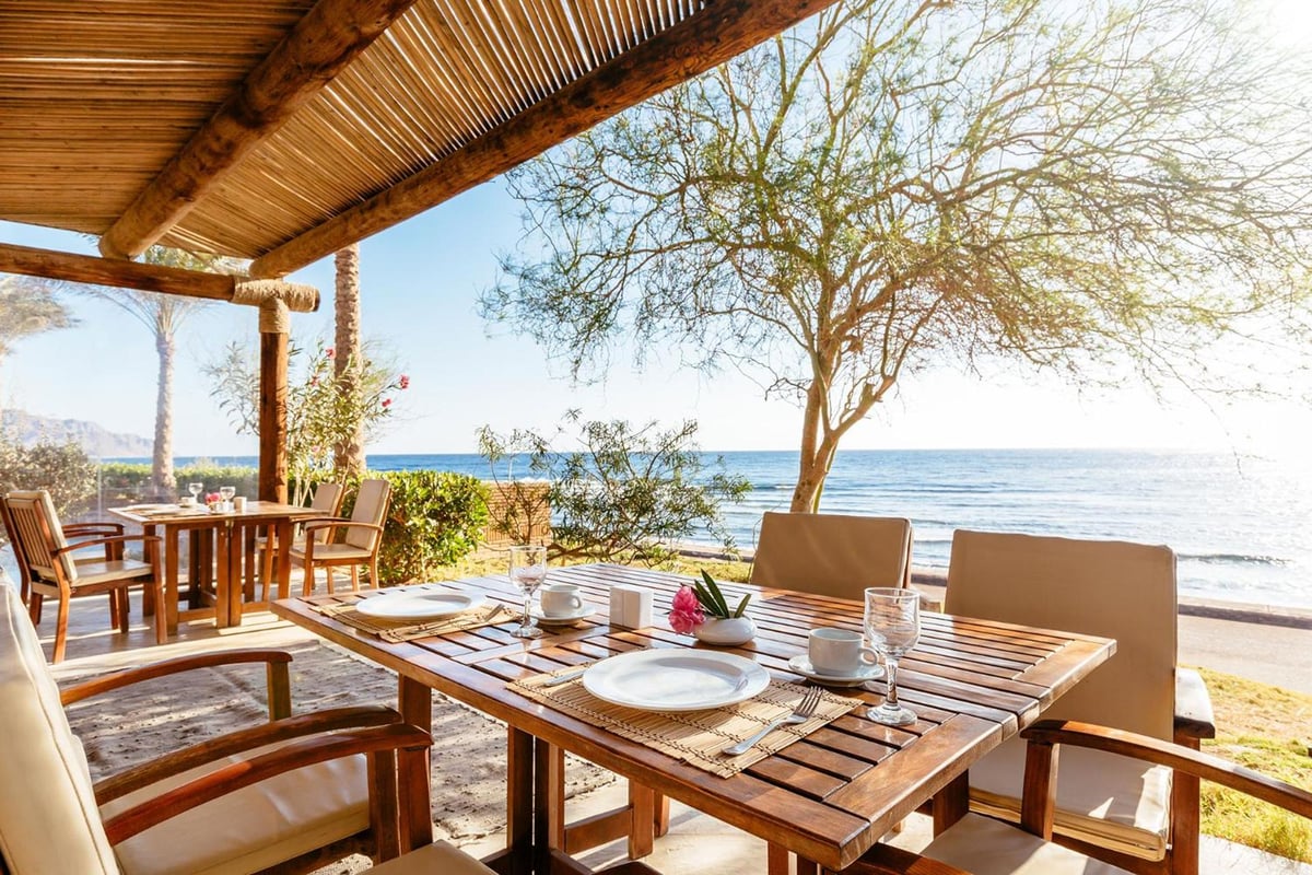 Dahab Paradise outdoor dining area with a wooden pergola and sea view.