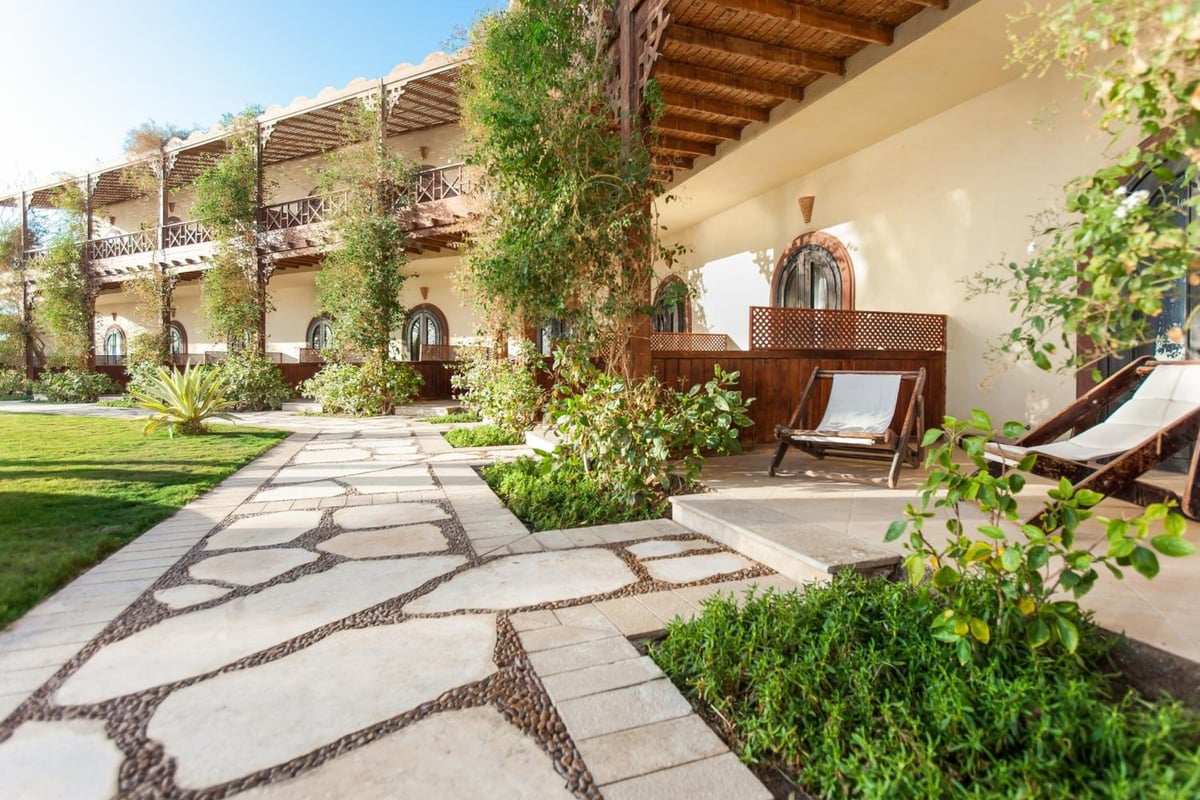 Dahab Paradise garden walkway with a stone path and wooden pergola.