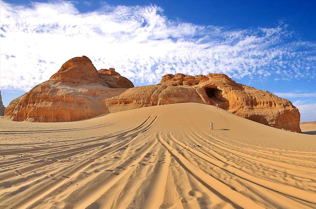Dahab Paradise desert landscape with rock formations and tire tracks.