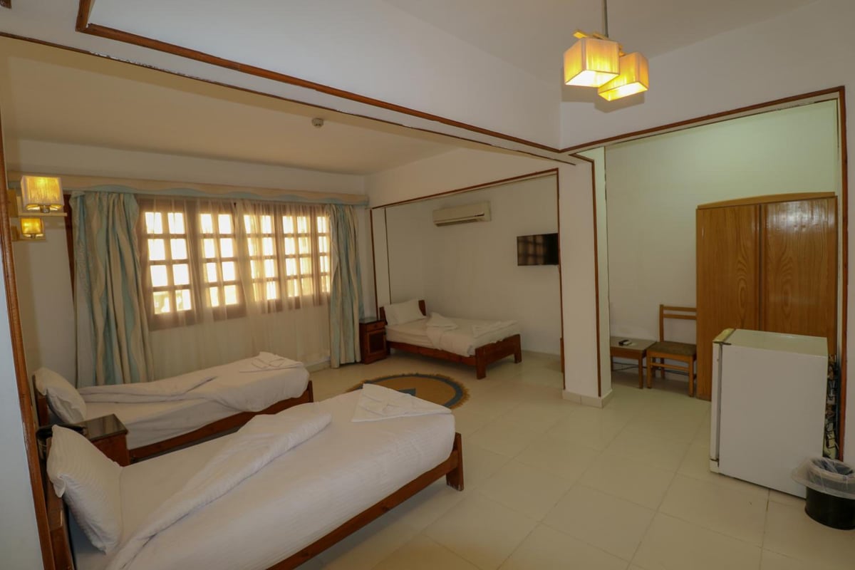Acacia Dahab Hotel guest room with three beds and a curtained window.
