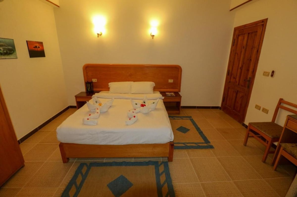 Acacia Dahab Hotel bedroom with a wooden bed and tiled floor.
